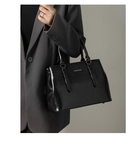 Detail view of glossy black faux leather tote with dual handles and fashion text logo