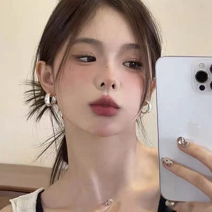 Mirror selfie showing the silver brushed metal hoop earrings with a minimalist design