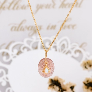 Macro detail of natural strawberry quartz pendant with opal stone on gold silver chain