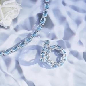 Detail of light blue oval gemstone necklace and ring set on elegant white silk background