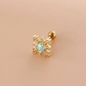 Detail view of a gold cross earring with a green opal stone and cubic zirconia accents
