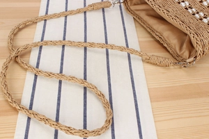 Détail du sac en paille tissé montrant les perles blanches, la doublure et la bandoulière