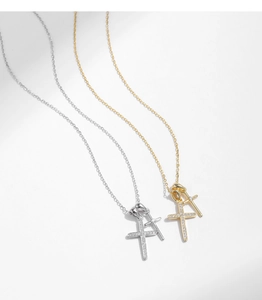 Détail des colliers double croix en argent et or avec cristaux brillants sur chaînes fines