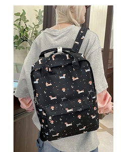Detail of dachshund and bow print backpack on model showing back-side casual wear style