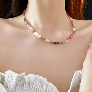 Detail of beaded bamboo-style pearl necklace with colorful natural stones on skin