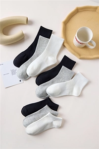 Flat lay of cotton socks in black, white, and grey with ribbed cuffs on minimalist background