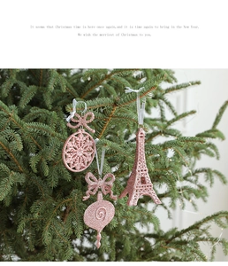Pink glitter Eiffel Tower and bow ornaments hanging on a festive green Christmas tree
