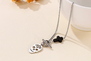 Macro detail of silver skull pendant with black cross and OT toggle clasp closure