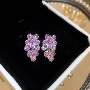 Nahaufnahme von violetten Kristall-Blumenohrringen in Gold auf schwarzem Samt