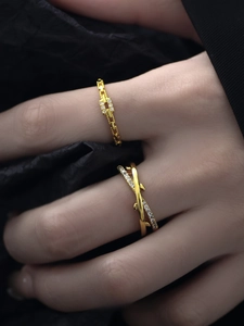 Detailed view of two gold-plated rings with zircon pavé on a black textured backdrop