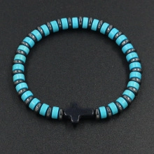 Detail of handcrafted blue and grey beaded leather cord bracelet with black cross charm