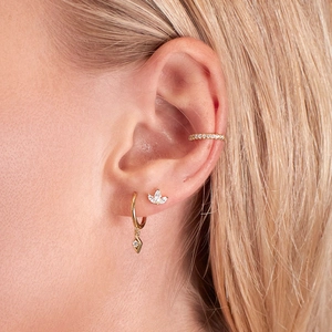 Close-up of gold ear cuff, clover stud, and drop earring set with diamonds on model