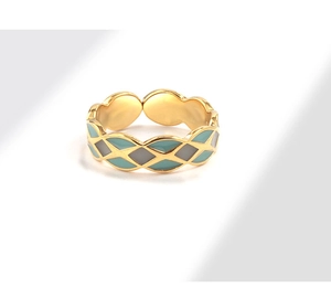 Close-up of geometric enamel grid ring featuring cyan and grey pattern on golden metal