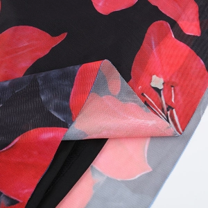 Detailed macro view of the breathable mesh fabric with vibrant red floral print and black lining