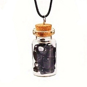 Detailed close-up of a glass wish bottle pendant with black obsidian stones and a cork top