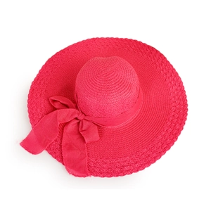 Close-up of woven straw sun hat texture with a large magenta satin ribbon bow