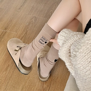 Close-up of khaki crew socks with Follow Your Heart embroidery and small black heart
