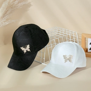 Detail of baseball caps with rhinestone butterfly decor and jacquard fabric texture