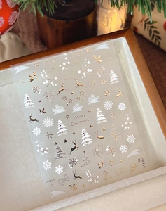 Détails de stickers nail art de Noël avec motifs de rennes dorés et flocons de neige