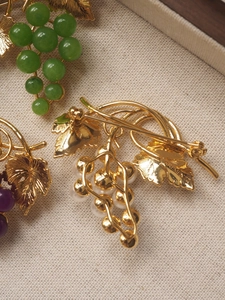 Detail of vintage grape brooches in gold finish with green, purple and white pearls