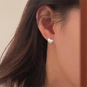 Close-up of minimalist brushed silver heart stud earring worn on the earlobe