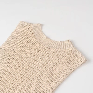 Détail de la robe en maille beige montrant le col rond et le motif tricoté ajouré texturé