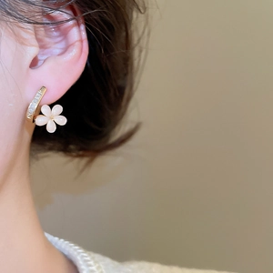 Detail of 18k gold plated flower stud earrings with sparkling zircon and cat eye petals