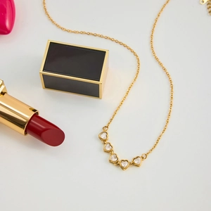 Golden heart necklace with zircon pendants styled with lipstick and luxury gift box