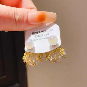 Détail de boucles d'oreilles couronne dorées avec perles et cristaux sur carte de support