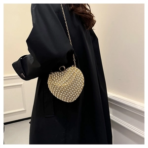 Detailed view of rhinestone heart evening bag with metal chain on a black coat