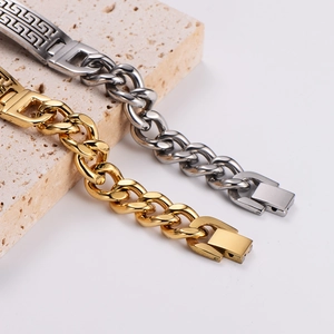 Gold and silver Cuban chain bracelets with Greek fret patterns on beige travertine stone