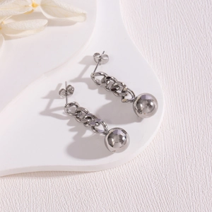 Detail of silver long drop earrings with polished sphere and metallic curb chain links