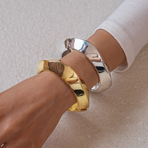 Close-up of gold and silver chunky geometric metal cuffs on a model wrist