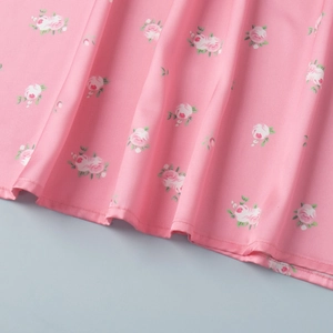 Close-up of pink floral satin fabric with rose print and fine stitching details
