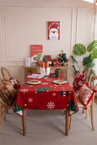 Detailed view of red Christmas tablecloth with snowflake and tree patterns and pillows
