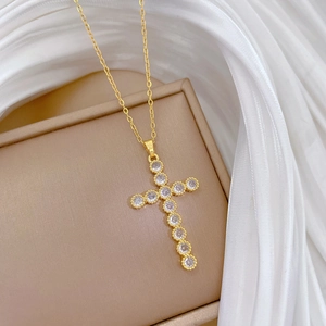 Detailed macro view of a gold cross pendant with clear cubic zirconia in bezel setting