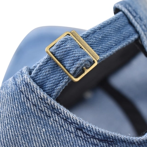 Detailed macro shot of vintage metal buckle on blue washed denim baseball cap