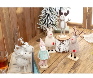 Macro detail of handmade wool felt reindeer and gnome figures on rustic wooden bases