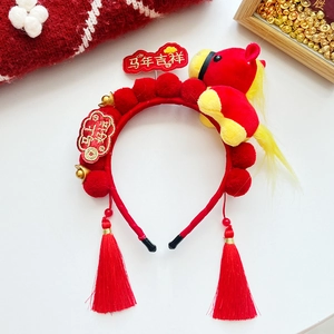 Detail of red New Year headband with plush horse, golden bells and festive tassels
