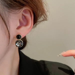 Close-up of vintage geometric earrings with black and grey crystals on a female model