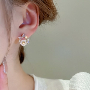 Close-up of floral stud earring with bow and pearl on model showing refined details