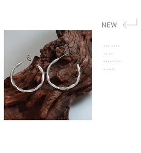 Detailed view of silver bamboo-joint C-shaped hoop earrings with a matte metallic finish