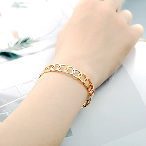 Close-up of a gold titanium steel open bangle with interlocking hollow circles on a wrist.