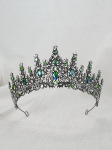 Close-up of green rhinestones and crystals on a black metal princess crown headpiece