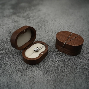 Detail of oval walnut wood jewelry box with silver pavé cylinder necklace inside