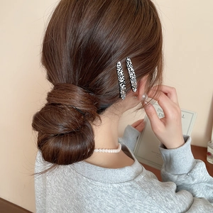 Dettaglio di eleganti fermagli per capelli in acrilico a pois bianchi e neri su uno chignon