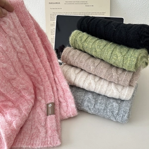 Detail of cable knit wool scarf texture and brand label in sweet candy colors