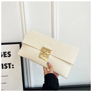 Détail d'une pochette enveloppe blanc cassé avec motif crocodile et fermoir doré