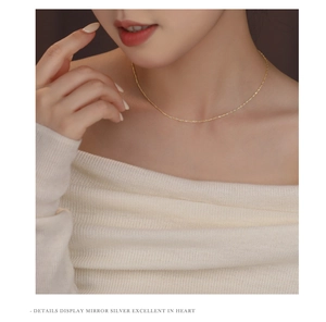 Detail showing the delicate 18K gold plated water wave chain on a model neck