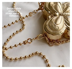 Detail of gold butterfly bag with detachable beaded chain strap and metal clasp